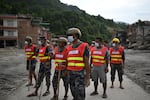 Rescue team personnel search through debris and mud covering an area following flash floods in DeviGhat village, Nepal.