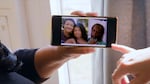 Shalana Jordan holds a photo of her parents Nola and Robert Ramsuer displayed on her phone.