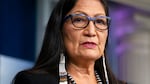 Interior Secretary Deb Haaland, wearing glasses, earrings and a beaded necklace, speaks during a news briefing at the White House in Washington.