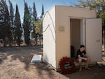 A boy sits beside a wreath that reads "Kibbutz Nir Oz" at the funeral.