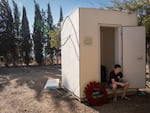 A boy sits beside a wreath that reads "Kibbutz Nir Oz" at the funeral. 