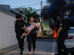 Israeli police officers evacuate a woman and a child from a site hit by a rocket fired from the Gaza Strip, in Ashkelon, southern Israel, Saturday, Oct. 7, 2023. The rockets were fired as Hamas announced a new operation against Israel.