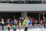 Coach Alec Schmitt embraces one of his students as skaters gather on the ice at the end of the final show at the Lloyd Center Ice Rink, May 31, 2026. The ice arena was the first mall ice rink in the world, opened in 1960. 