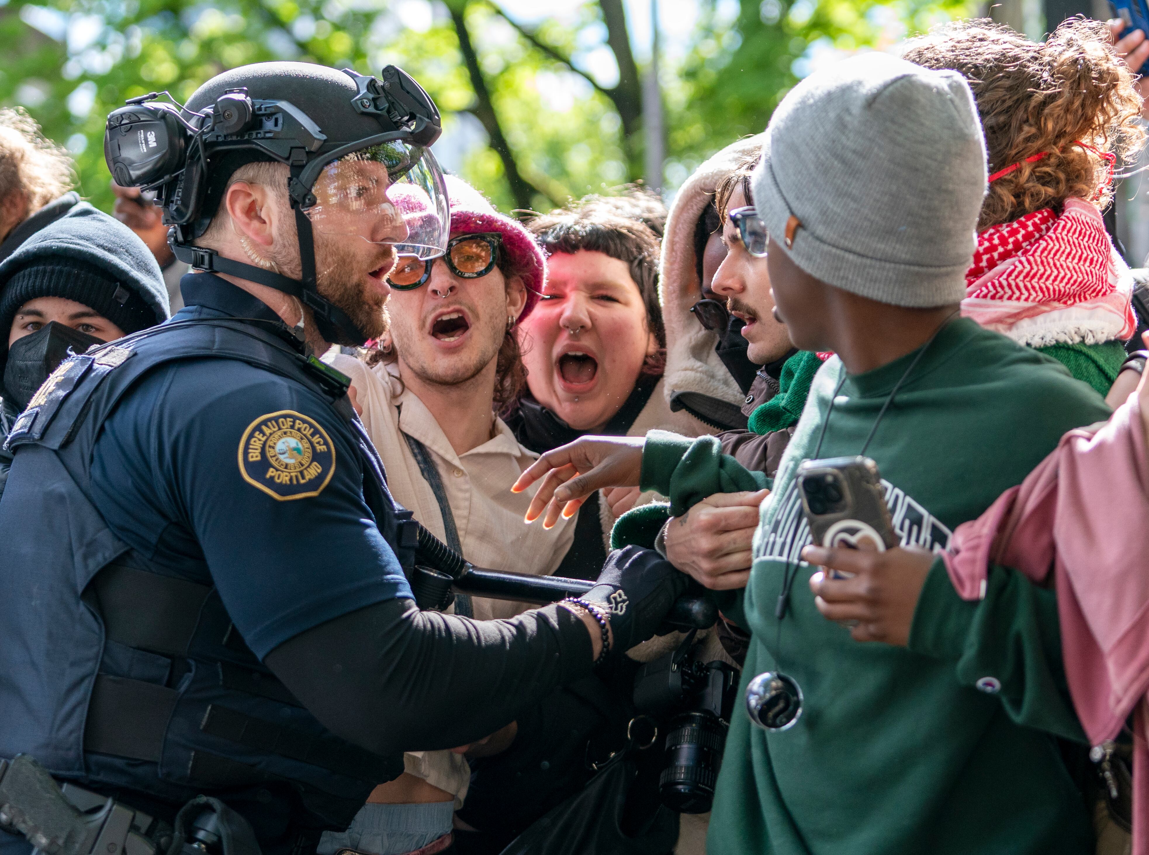 People attempt to stop a white van carrying detained protesters. Law enforcement teams clear protesters from Portland State University’s Branford Price Millar Library, May 2, 2024. Demonstrators protesting the war in Gaza have occupied the library since Monday evening.