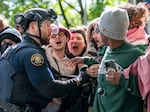 People attempt to stop a white van carrying detained protesters. Law enforcement teams clear protesters from Portland State University’s Branford Price Millar Library, May 2, 2024. Demonstrators protesting the war in Gaza have occupied the library since Monday evening.