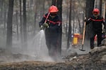 A firefighter sprays water after a wildfire in the region of the Fontainebleau forest, south of Paris, France, Tuesday, July 14, 2026.