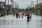 Residents wade through a street flooded in the passing of Hurricane Helene, in Batabano, Mayabeque province, Cuba, Thursday, Sept. 26, 2024.