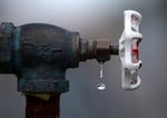 This photo shows a close-up of a water faucet with a stray drop of water dripping from it.