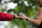 A runner grabs nuun energy drink from a volunteer during the Portland Marathon in Portland, Ore., Sunday, Oct. 6, 2019. The marathon's new route traveled through the Sellwood neighborhood.