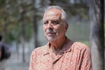Photographed from about the torso up, Rocco Fertoli is wearing an orange and cream patterned, button-down shirt. He has gray hair and a gray goatee.
