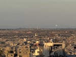 A large Israeli flag waves in the distance over a landscape of destruction and debris in Gaza near the border with Israel.
