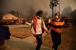 Residents walk past homes burnt by the Eaton Fire.