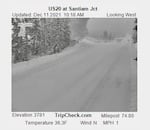 White snow blankets a road, with tire tracks visible and snowy trees on both sides of the road. Text on the image says the elevation is 3,781 feet and the temperature is 36.3 degrees Fahrenheit.