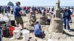The Jessops work on their sandcastle as OPB — and the crowd— watches. Will their arches remain standing?