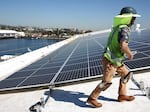 Workers install solar panels on a rooftop at AltaSea's research and development facility at the Port of Los Angeles on April 21, 2023.