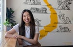 Kim Dam, the owner of Portland Ca Phe, sits in front of a painting of Vietnam in her coffee shop.