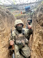 A provided photo from September, 2025, showing unidentified soldiers in a trench in Ukraine, point out how a fishing net protects them against a drone carrying explosives.