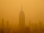 Smoky haze from wildfires in Canada obscures New York City's Empire State Building this year. The air in the U.S. has improved over the past 50 years, but smoke pollution from growing wildfires erodes much of that progress.
