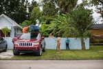 Allan Juhl gets help tying up his canoe while his partner Katie Falcon and their neighbors Ashley Palacios and her brother Andres Garcia look on Sept. 27, 2022, in the Palmetto Beach neighborhood of Tampa, Fla., before Hurricane Ian hit the area.