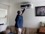 Alpine Heating & Air Conditioning General Manager Cody Calavan is inspecting a heat pump unit he installed at an affordable housing property owned by St. Vincent de Paul. The company teamed up with the nonprofit to install more than 150 heat pump units for qualified renters. Pictured on March 27, 2025.
