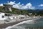 Tourists sunbathe on a beach near a telescope of the Crimean Astrophysical Laboratory in Simeiz, Crimea. The Black Sea peninsula is normally packed with visitors in the summer. But Ukraine's drone attacks, and the disruption of daily services, has kept many tourists away this year.