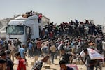 Displaced Palestinians carry food parcels as they raid trucks carrying humanitarian aid in Khan Yunis, in the southern Gaza Strip on Aug. 9, 2025.
