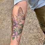 Tyler Clouse shows off his Oregon silverspot butterfly tattoo, with the early blue violet which caterpillars rely on and the dune tansy (yellow) that adults use for nectar.