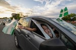 A supporter waves a Puerto Rican Independence Party flag while holding a campaign poster promoting the Citizens' Victory Movement mayoral candidate Manuel Natal, during a caravan in San Juan, Puerto Rico, Friday, Nov. 1, 2024.