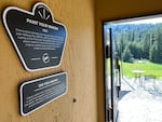 The "Paint Your Wagon" marker is hung up  on a wood paneled wall lit by an open door revealing the forested mountain and green grasses outside.