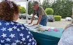 Doug Hicks signs a initiative petition on June 3, 2026 in Tumwater, Washington. The proposed ballot measure would repeal a statewide income tax on high earners enacted earlier this year.