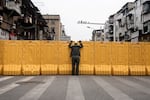 One man talks to another man on March 8, 2020, through a makeshift barricade wall built to control entry and exit to a residential compound in Wuhan, Hubei, China.