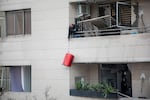 A man lowers a suitcase from the balcony of a building damaged by a strike in a commercial district of Tehran, Iran, during the U.S.-Israeli war on Iran, Sunday.