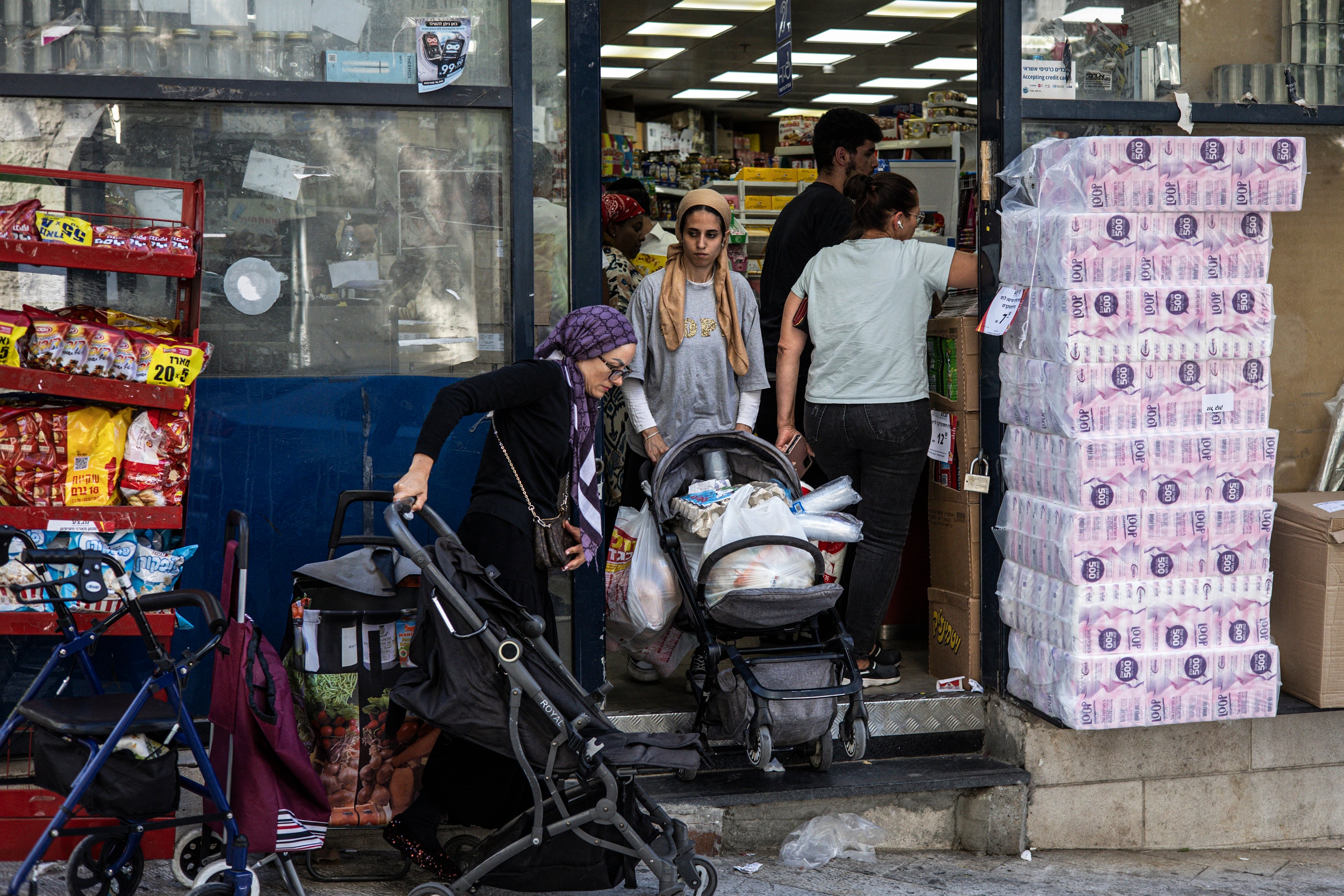 A woman pushes a stroller full with goods as people stock up with supplies, at a shop in Jerusalem, on June 13, 2025.