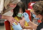 Kelly Leung, 11, is reassured by Multnomah County health officers as Leung receives vaccinations at a catch-up vaccination clinic in 2023. Oregon is resuming eligibility checks for people on Medicaid which includes about half of Oregon's children. Starting this year, they can stay enrolled until their 6th birthday.