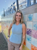 Jen Goodlin, executive director of the Rebuild Paradise Foundation, poses with a mural depicting a sunset from handprints of local children, at Paradise Community Park in November 2024.