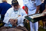 FILE - Pearl Harbor survivor Ira "Ike" Schab, 104, from Beaverton, Ore., looks at a photo presented by an attendee after the 83rd Pearl Harbor Remembrance Day ceremony, Saturday, Dec. 7, 2024, in Honolulu.