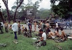 As victorious North Vietnamese troops ride past on a tank, defeated South Vietnamese troops discard their uniforms in Saigon, April 30, 1975, the day the South Vietnamese capital fell to communist forces, ending the Vietnam War. (AP Photo/Yves Billy)