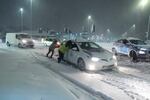 People help to push cars stuck in snow in Leeds, England, Sunday, Jan. 5, 2025.