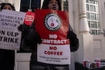 People hold signs outside of a closed Starbucks as employees strike on Monday in New York City.