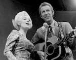 Country singer Dolly Parton and her collaborator Porter Wagoner perform onstage in circa 1967. Mr. Wagoner is wearing a Nudie Suit designed by Nudie Cohn of Nudie's Rodeo Tailors.