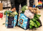 A client at the No Limits Food Pantry distribution center carries a bag of fresh produce and can goods they received.