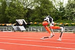 A robot runs on an orange track.