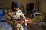 A soldier with the HTS shows how Captagon pills fit into the pill holders scattered across the floor in the facility.