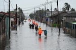 People walk through a flooded street in Batabano, Mayabeque province, Cuba on August 29, 2023, during the passage of tropical storm Idalia.