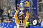Sisay Lemma, of Ethiopia, displays the trophy on the finish line after winning the Boston Marathon, Monday, April 15, 2024, in Boston.