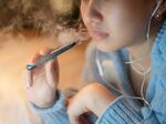A young woman vapes an electronic cigarette. Some districts are installing high-tech vape detectors to alert school officials if students are using e-cigarettes.