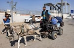 A journalist films a man driving a donkey-drawn cart carrying luggage outside the Rafah border crossing with Egypt in the southern Gaza Strip on Wednesday.