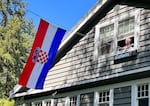 Ted Kaye hoists a Croatian flag from his second-story window at his Forest Park home in Northwest Portland, where it hangs over the street. He display information about the flag on a display board for his neighbors.