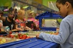 Students at Rigler School select their daily required servings of fruits and veggies from a salad bar.