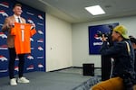 Quarterback Bo Nix holds up a jersey for photographers after a news conference with the Denver Broncos NFL football team Friday, April 26, 2024, in Centennial, Colo. The Oregon quarterback is one of several Pac-12 players recently drafted by an NFL team.